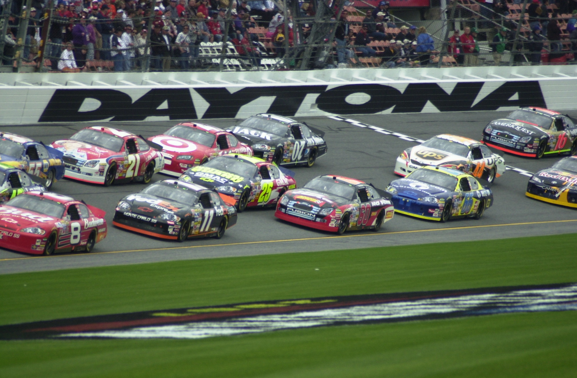 A pack of stock cars racing at Daytona International Speedway